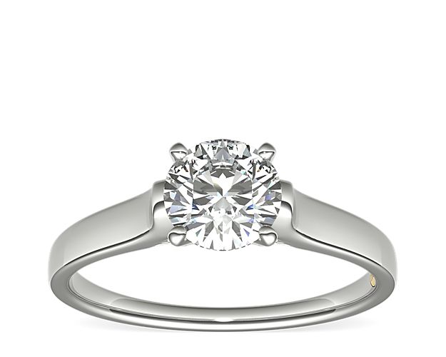 Classic with a touch of sparkle, this platinum solitaire engagement ring features a pavé-set diamond bridge. Zac infuses luxurious style by adorning each ring with a signature 18k yellow gold interior accent.