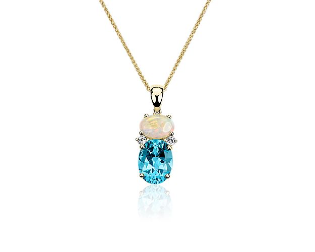 Showcasing a cabochon opal, oval Swiss Blue topaz, and accented with white sapphires, this 14k yellow gold pendant finishes any look with decadent color.