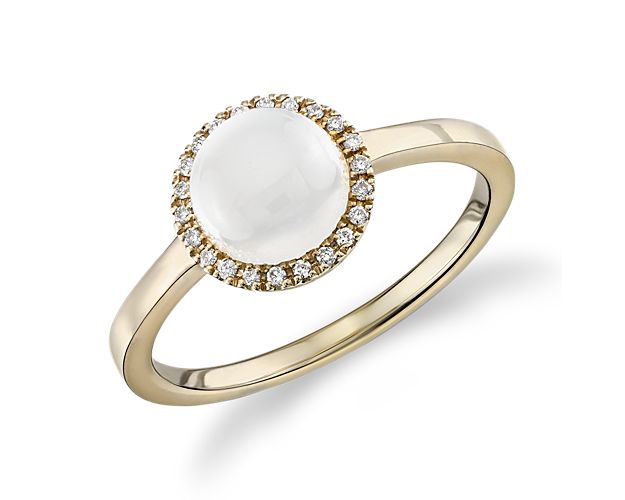 The soft, lustrous color of this round-cut white moonstone cabochon is accentuated by a dazzling diamond halo and a gleaming 14k yellow gold setting.