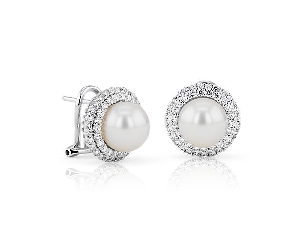 Dual halos of brilliant round diamonds set in 18k white gold surround a lustrous Akoya pearl for a luxe, sophisticated look. Omega backings provide extra security when wearing.