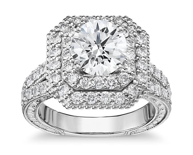 This platinum engagement ring is an absolute stunner! A double halo of round diamonds sits atop a split shank paved with asscher-cut diamonds. The side view shows off delicate milgrain and etched details as well as a bezel set diamond for extra sparkle. This setting is custom made to fit your beautiful center stone.