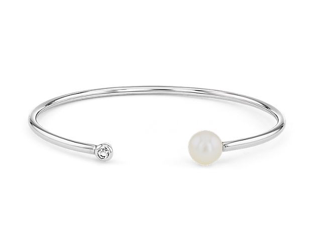 This sterling silver cuff bracelet showcases tips of a lustrous Freshwater pearl and a sparkling white topaz.