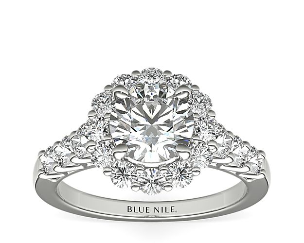 This royal display of brilliance features your center stone surrounded by a halo of 12 diamonds with an additional 6 diamond side stones running along the shoulders on a band of polished platinum.