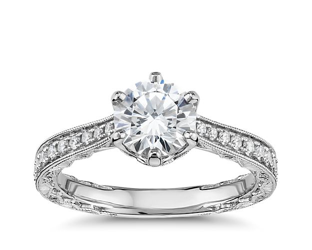 Bright, regal 14k white gold is delicately engraved and decorated with milgrain details and presents your chosen diamond set with six scalloped prongs. Twenty-six diamonds over the bridge and along the band add additional sparkle and beauty.  