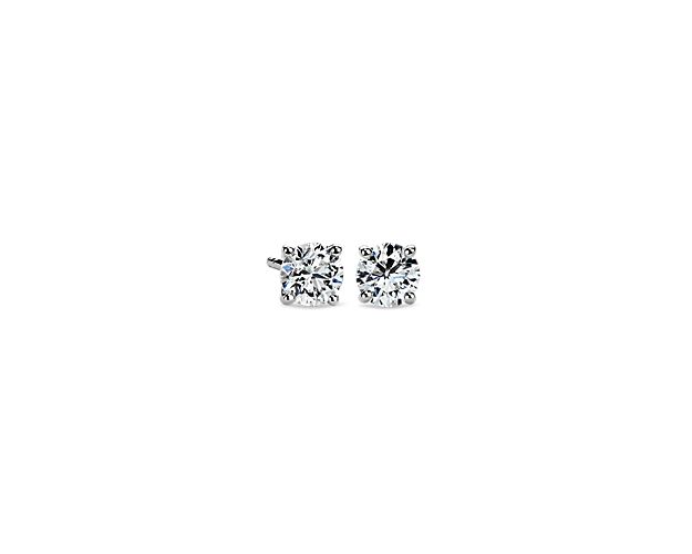 A perfectly matched pair of round, near-colorless diamonds are secured in platinum four-prong settings with guardian back and posts for pierced ears. Each earring weighs roughly 1/2 carat, for a total diamond weight of 1 carat.