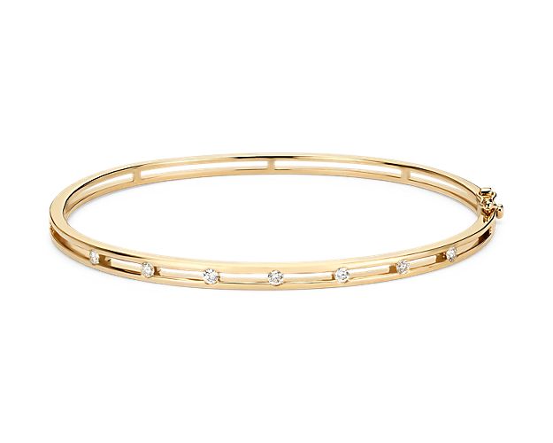 Delicately set in 14k yellow gold, this bangle has seven stationed diamonds for a little touch of elegance. The diameter of this bangle is 2 1/3" x 2".