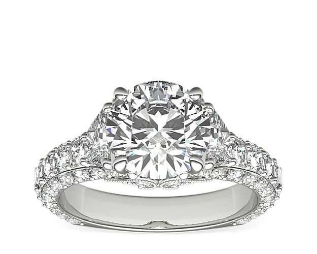 Opulent in design, this three-stone platinum diamond engagement ring showcases two trapezoid-shaped diamonds framing the round center stone diamond of your choice. An exceptional triple-row band features a striking asscher-cut diamond channel. This setting is custom made to fit your beautiful center stone.