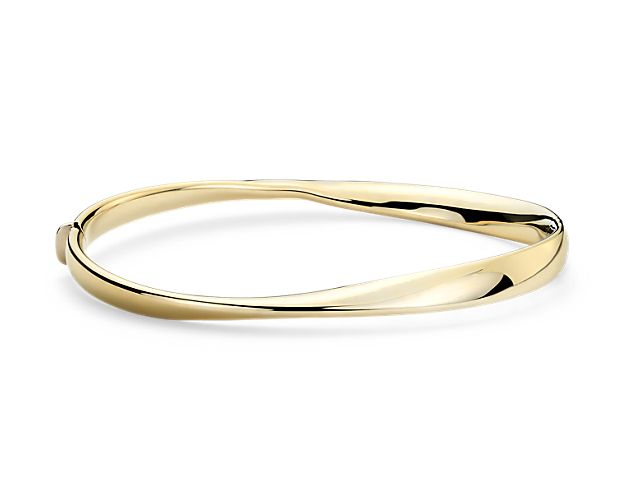 Uniquely twisted and Italian crafted, this lightweight bangle bracelet is crafted in hollow 14k gold with a hinge clasp.
