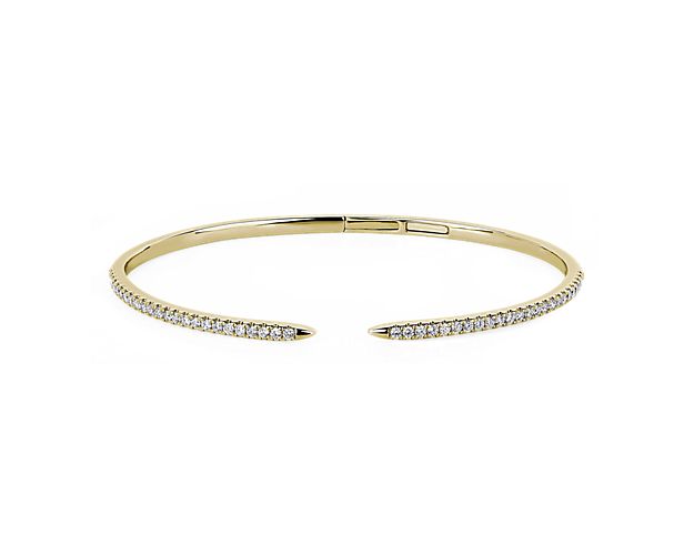 Catch the light with this delicate bangle lined with stunning diamonds that shimmer as you move. The gracefully slender 14k yellow gold design ends in an elegantly open claw design.
