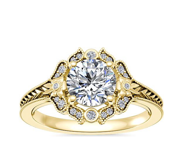 Crafted from luxurious gleaming 18k yellow gold, this engagement ring features intricate milgrain detailing. A floral-engraved halo beautifully complements the center stone with unique allure.