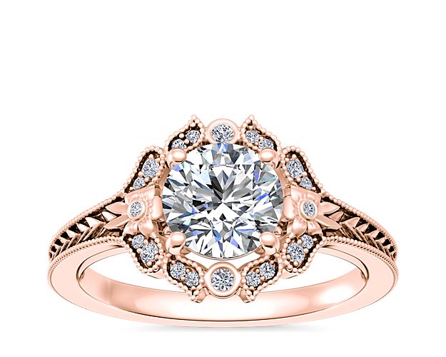 Capture the beauty of your love with this stunning engagement ring boasting a floral-engraved halo framing the center stone. The gleaming 18k rose gold design is delicately detailed with intricate milgrain accenting.