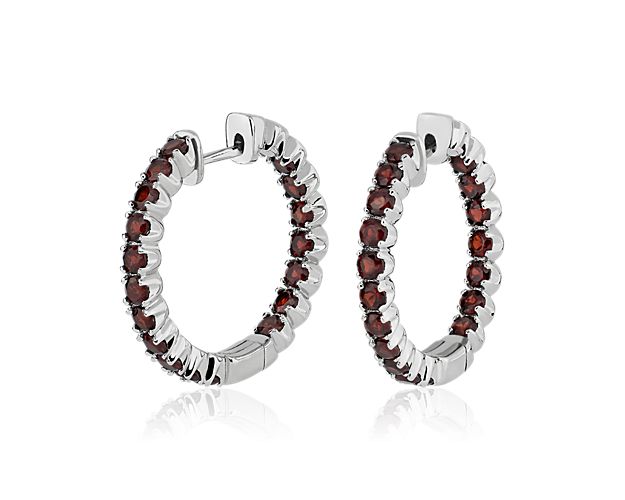 Brilliant garnets gleam along the front-facing edges of these elegant hoop earrings. They are crafted from lustrous sterling silver for a sophisticated look.