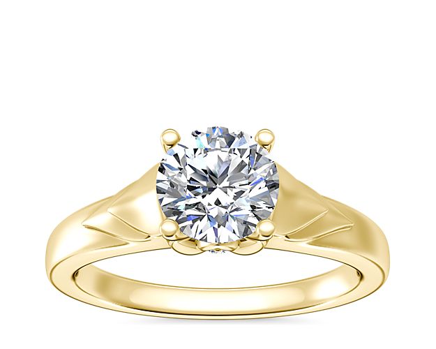 Love shines brilliantly in this solitaire engagement ring featuring a unique chevron design in gleaming 14k yellow gold. A hidden accent diamond shimmers at the side, adding elegance.