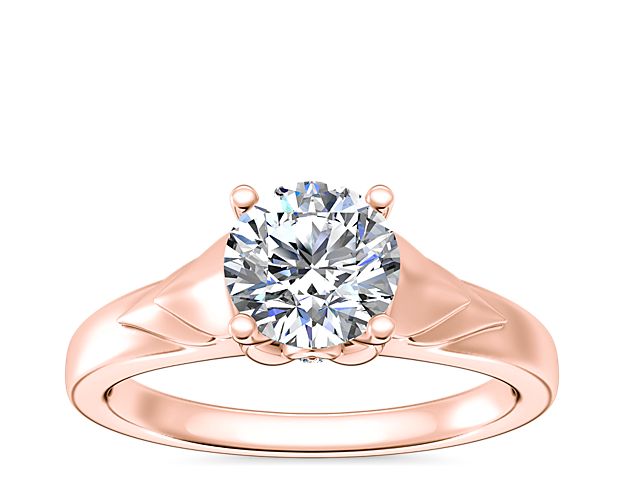 Love shines brilliantly in this solitaire engagement ring featuring a unique chevron design in gleaming 14k rose gold. A hidden accent diamond shimmers at the side, adding elegance.