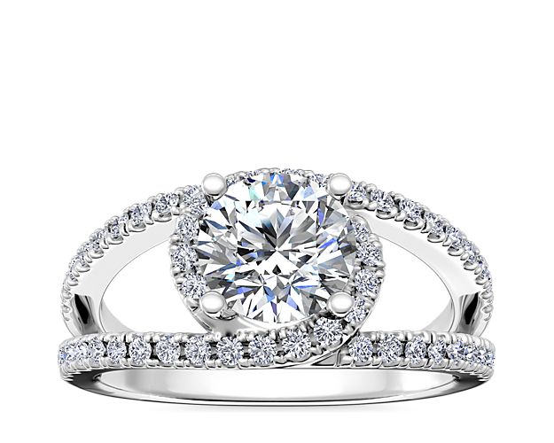 This gorgeous engagement ring features a platinum gold design with a split shank that interlocks around the stunning center diamond. Each split arm of the shank sparkles with delicate pave-set diamonds.