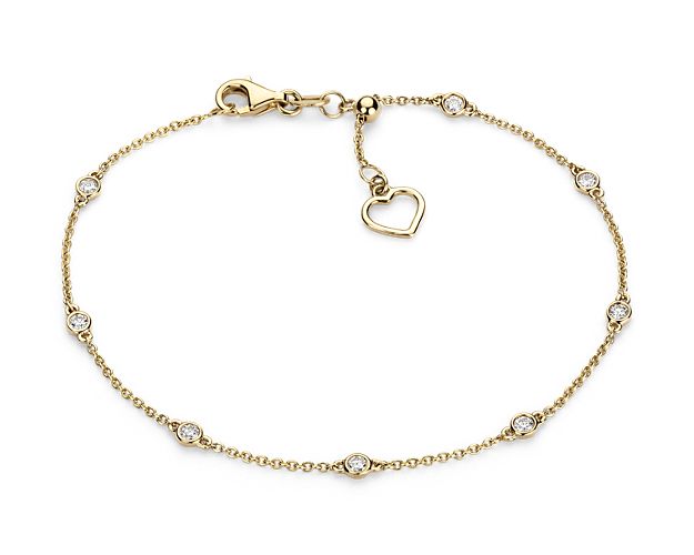 Eight petite bezel-set diamonds are stationed around a 14k yellow gold cable chain featuring a delicate heart accent that can be pulled to adjust the length of the bracelet.