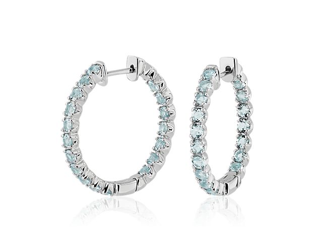 Bright and brilliant sky blue topaz stones line the front-facing edges of these delicate hoop earrings. The cool gleam of the sterling silver design beautifully complements the stones.