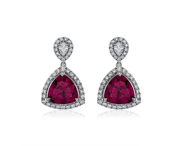 These beautiful earrings showcase two Trilliant cut garnets surrounded by a shimmering diamond halo.  Set in 18k white gold, this unique piece adds the perfect pop of color to your outfit!