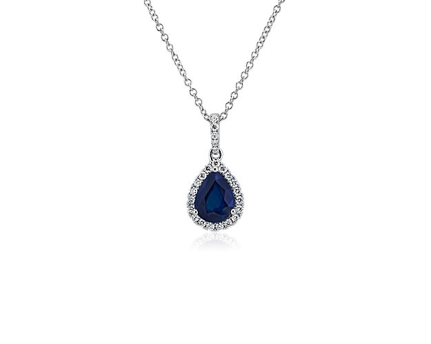 This sapphire drop pendant has timeless romance with its deep hue and dainty pear shape. The main stone is surrounded by a halo of diamonds and set into shining 14k white gold.