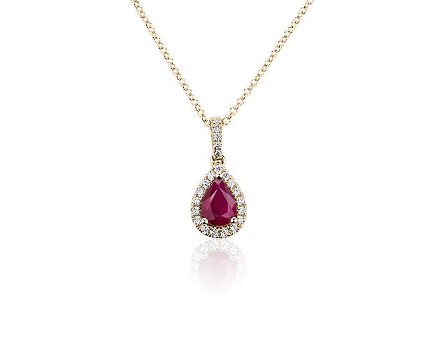 The rich red tone of the pear-cut ruby at the heart of this pendant is sure to mesmerize. Shimmering accent diamonds form a halo around it and sparkle along the bale of the yellow gold design.