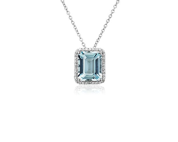 A gorgeously blue emerald-cut aquamarine shimmers in a stunning halo, giving this pendant necklace a breath-taking style. It is crafted in 14k white gold that offers luxurious quality and a beautiful cool lustre.