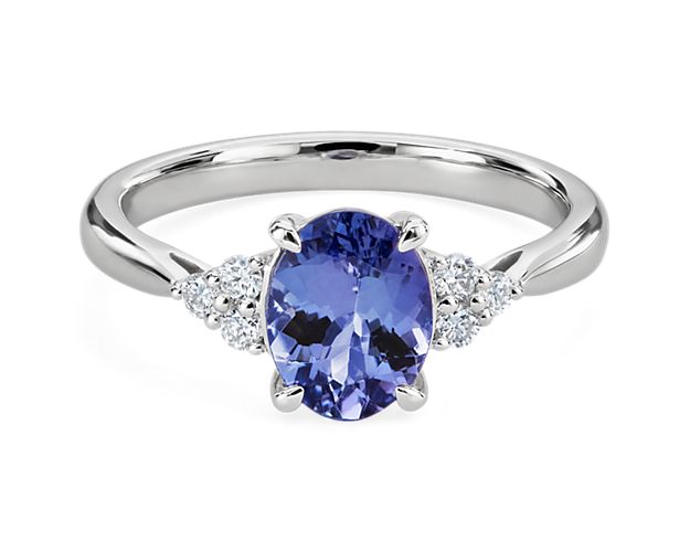 A beautifully blue oval-cut tanzanite stone sparkles at the centre of this stunning ring, accented by delicately shimmering accent diamonds on each side. The 14k white gold design ensures enduring luxurious quality.