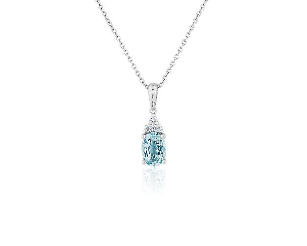 A beautifully blue oval-cut aquamarine shimmers at the heart of this pendant necklace, with a diamond cluster accentuating it with brilliant sparkle. Cooly gleaming 14k white gold design promises enduring quality.