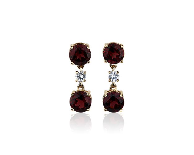 These elegant drop earrings feature dramatic garnet stones dangling with a white sapphire accent adding sparkle. They are designed in 14k yellow gold that promises a look of classic luxury and lasting quality.
