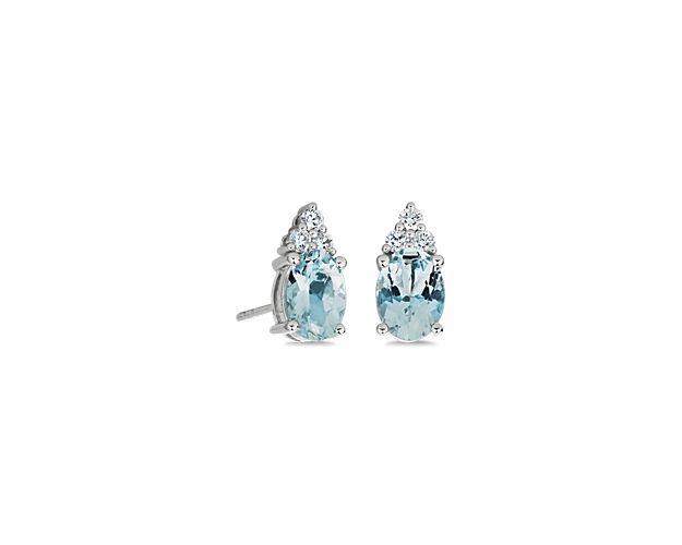 Shimmering in stunning style, these stud earrings each are set with an oval-cut aquamarine stone and accented by a shimmering cluster of diamonds. They are crafted in 14k white gold for lasting quality and beauty.