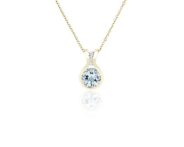 Shimmer in the light when you wear this elegant pendant set with a stunning round-cut aquamarine stone boasting a blue hue. 14k yellow gold gives the chain and the curving design a luxurious lustre.