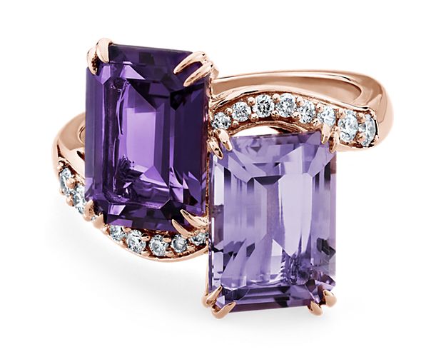 This exquisite rose gold two-stone ring features two stunning emerald cut amethyst gemstones adorned with glistening diamonds.  The amethyst gemstones are expertly cut to enhance their bold hue.