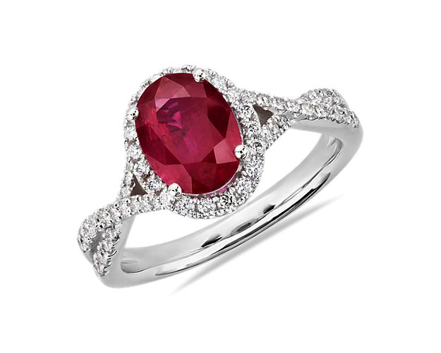 Bring bold elegance to your style with this ring featuring a gorgeous oval-cut ruby surrounded by a shimmering diamond halo. MicropavÃ© diamonds trail along the intricately twisting 14k white gold design, adding a touch of sparkle.